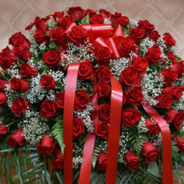 Large arrangement of red roses with white filler flowers and red ribbons