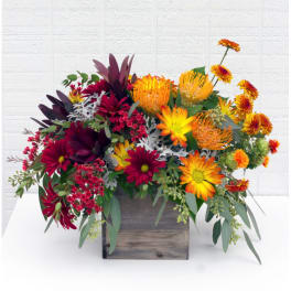 Mixed bouquet in a wooden box with orange, yellow, and burgundy flowers