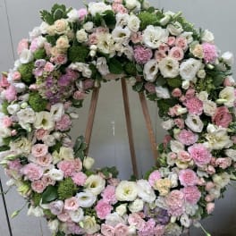 Large pastel floral wreath on an easel with pink and white blooms