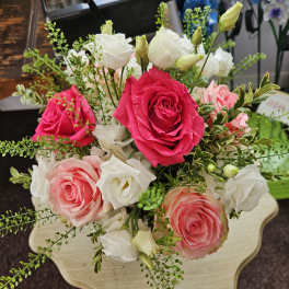 Low arrangement of pink and white roses with white hydrangeas on a wooden table