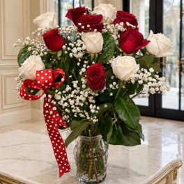 Red and white roses in a clear glass vase with a red polka-dot ribbon