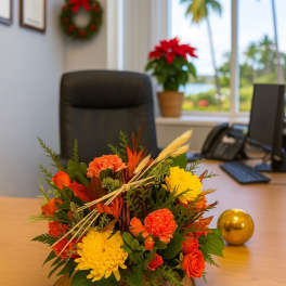 Low orange and yellow flower arrangement on a wood slice base on an office desk
