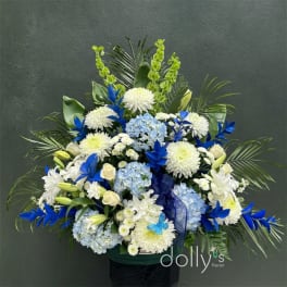 Large blue and white floral arrangement in a dark container