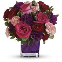 Bouquet of pink, red, and purple roses in a purple glass vase