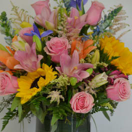 Pink roses, lilies, and sunflowers in a glass vase