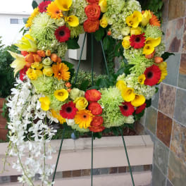 Large floral wreath on an easel with yellow, orange, red, and white blooms