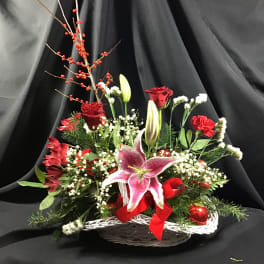 Basket arrangement with pink lilies, red roses, and red berries