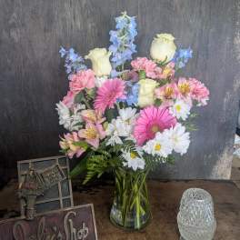 Mixed bouquet in a clear glass vase with pink, white, and blue flowers