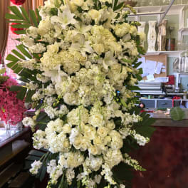 Large white floral standing spray with lilies, roses, and hydrangeas