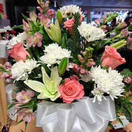 Bouquet of pink roses, white lilies, and white chrysanthemums with a white ribbon