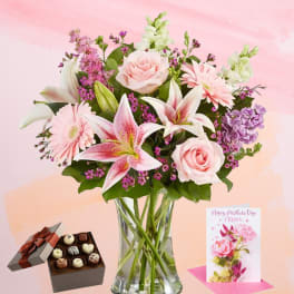 Pink and white mixed bouquet in a glass vase with chocolates and a greeting card