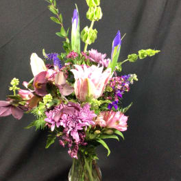 Mixed bouquet of pink, purple, and white flowers in a glass vase
