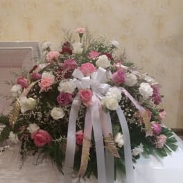 Large pink and white rose arrangement with ribbons on a table