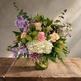 Mixed bouquet of pastel flowers in a clear glass vase