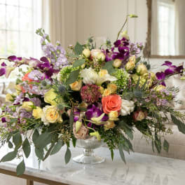Mixed bouquet of roses, orchids, and lavender flowers in a glass vase