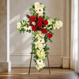 Cross-shaped floral arrangement with red roses and white flowers on an easel