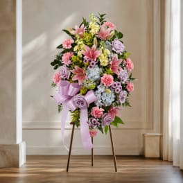 Standing floral spray with pink lilies, roses, and carnations on an easel