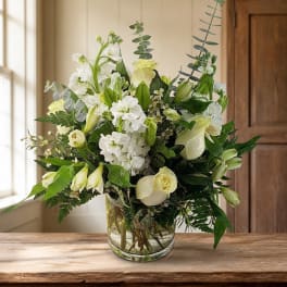 White and pale green floral arrangement in a clear glass vase