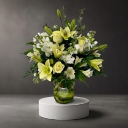 White and pale yellow floral arrangement in a glass vase