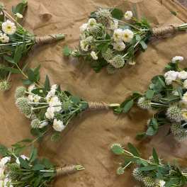 Small white flower bouquets with green foliage wrapped in twine