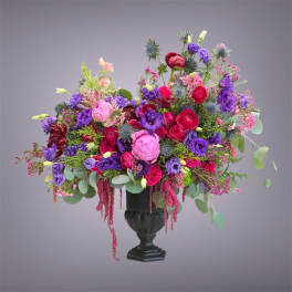 Colorful bouquet of pink, red, and purple flowers in a black urn vase