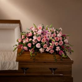 Pink rose and lily arrangement on a wooden casket