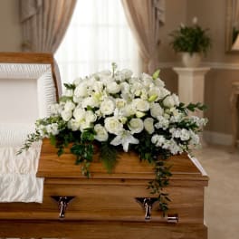 White rose and lily casket spray on a wooden coffin