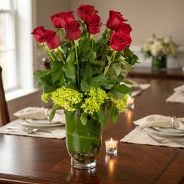 Red roses in a clear glass vase with green filler flowers