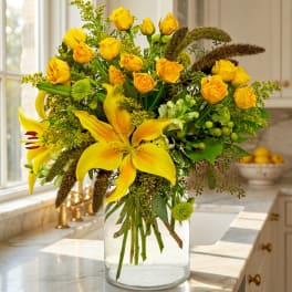 Yellow roses and lilies arranged in a clear glass vase