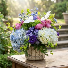 Mixed bouquet of hydrangeas, roses, and orchids in a ceramic vase