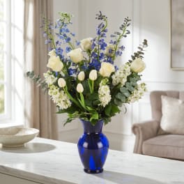 Blue and white flower arrangement in a cobalt vase