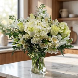 White and pale green bouquet in a clear glass vase