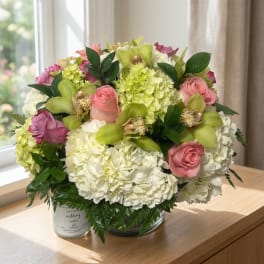 Bouquet of pink roses, white hydrangeas, and green orchids in a glass vase