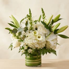 White floral arrangement in a striped glass vase with lilies and roses