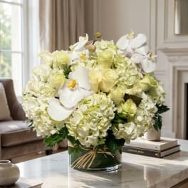 White and pale yellow floral arrangement in a glass vase