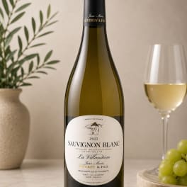 Bottle of white wine beside a glass and grapes