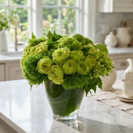 Green floral arrangement in a clear glass vase on a kitchen counter