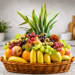 Fruit basket with pineapple leaves, grapes, bananas, apples, oranges, and rambutan