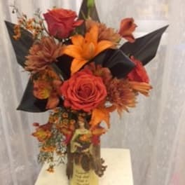 Orange and red floral arrangement in a vase with black wrap