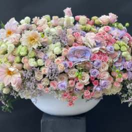 Large pastel floral arrangement in a white bowl vase