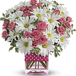 Pink roses and white daisies in a clear square vase with a polka-dot wrap