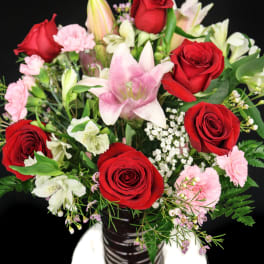 Bouquet of red roses, pink lilies, and carnations in a vase