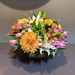 Mixed bouquet of orange, pink, and white flowers in a glass vase
