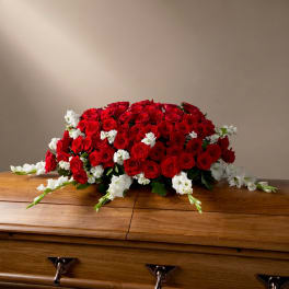 Red rose casket spray with white flowers on a wooden casket