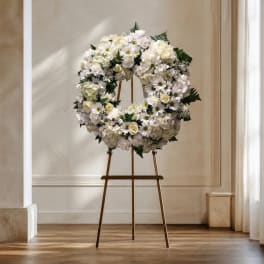 White floral wreath on a gold easel stand
