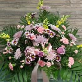 Pink and lavender funeral spray with mixed flowers and greenery