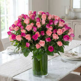 Pink and magenta roses arranged in a tall glass vase