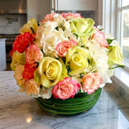 Mixed roses and white hydrangeas in a green glass bowl vase