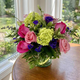 Bouquet of pink and purple roses with green hydrangeas in a glass vase