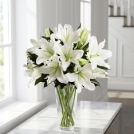 White lilies arranged in a clear glass vase